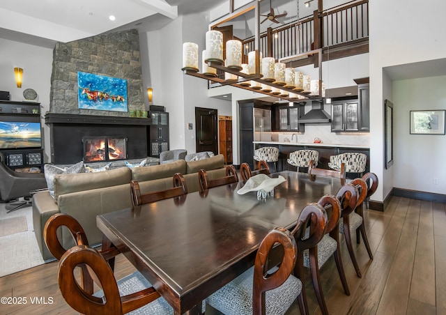 320 Hummingbird Dr Unit A201, Avon, CO 81620 - dining room with hardwood / wood-style flooring, a stone fireplace, a towering ceiling, and ceiling fan