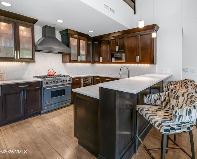 320 Hummingbird Dr Unit A201, Avon, CO 81620 - kitchen featuring wall chimney range hood, stainless steel appliances, beverage cooler, light wood-style floors, and a peninsula