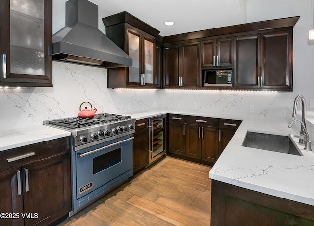 320 Hummingbird Dr Unit A201, Avon, CO 81620 - kitchen featuring appliances with stainless steel finishes, wall chimney range hood, wine cooler, light wood-style flooring, and light stone counters