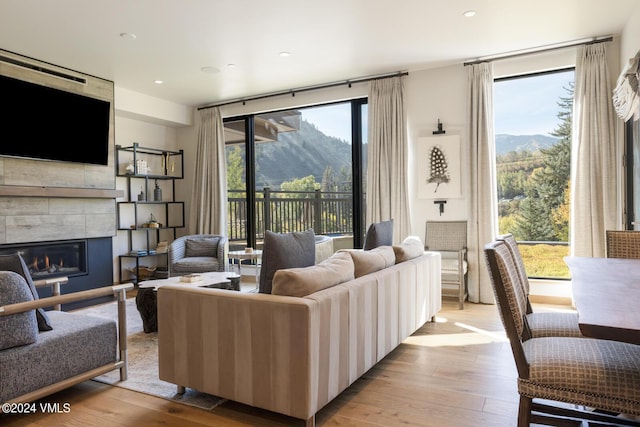 living room with a tile fireplace, a mountain view, and light hardwood / wood-style flooring