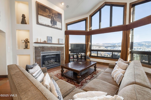 living room featuring wood-type flooring, a fireplace, and a high ceiling