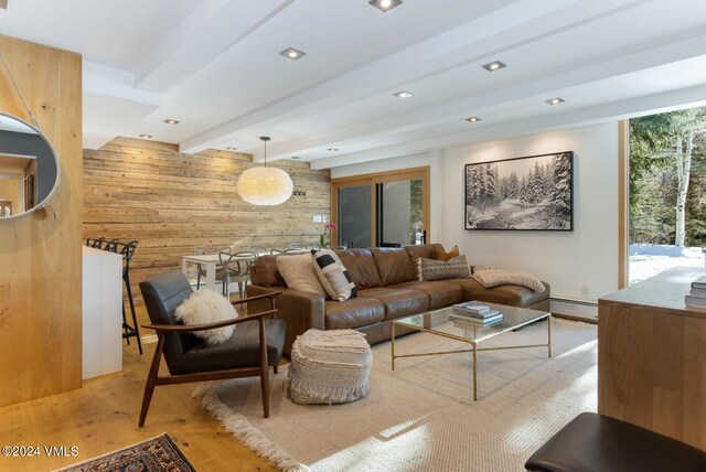 living room featuring baseboard heating, light hardwood / wood-style flooring, beamed ceiling, and wood walls