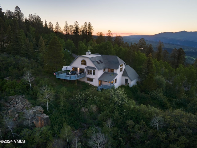 aerial view at dusk featuring a forest view and a mountain view