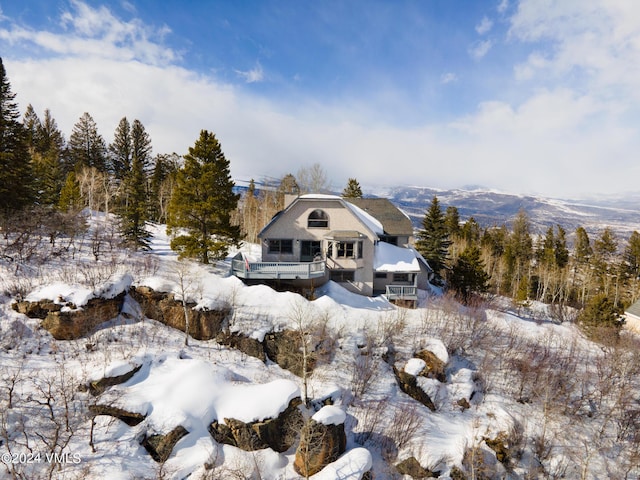 snow covered back of property featuring a deck and a chimney