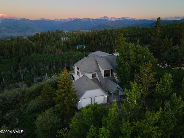 aerial view at dusk with a mountain view and a forest view