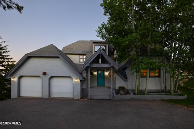 view of front facade featuring aphalt driveway, an attached garage, and stucco siding