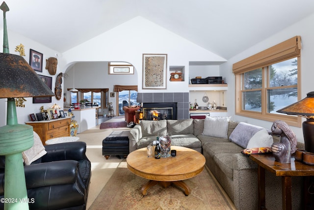 living area with a healthy amount of sunlight, a tile fireplace, and high vaulted ceiling