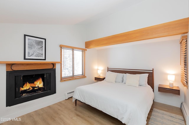 1610 Buffehr Creek Rd Unit A-22, Vail, CO 81657 - bedroom with lofted ceiling, a baseboard radiator, wood finished floors, and a lit fireplace