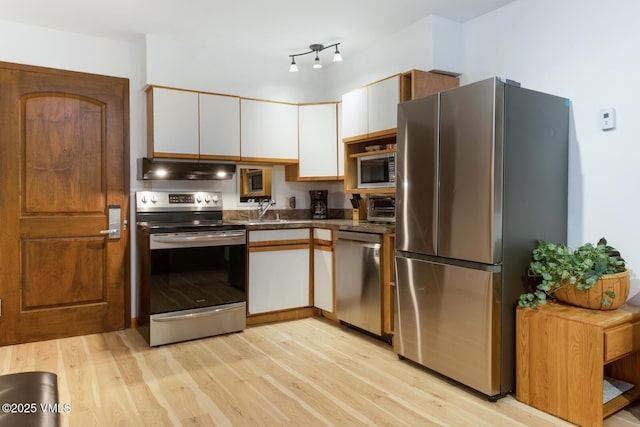 660 Lionshead Pl Unit 29, Vail, CO 81658 - kitchen featuring appliances with stainless steel finishes, under cabinet range hood, light wood-style floors, and white cabinetry