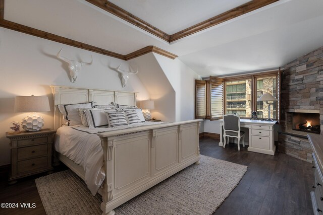 bedroom with a fireplace, built in desk, dark wood-type flooring, and ornamental molding