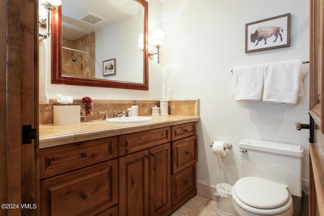 bathroom featuring vanity, toilet, tasteful backsplash, baseboards, and tile patterned floors