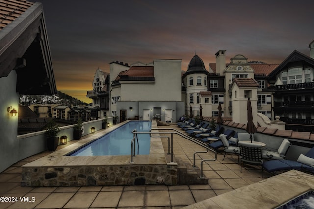 pool at dusk featuring a patio