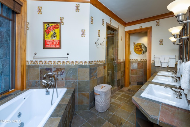 full bathroom featuring a stall shower, a whirlpool tub, a sink, crown molding, and tile walls