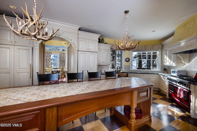 kitchen with range with two ovens, arched walkways, an inviting chandelier, and a healthy amount of sunlight