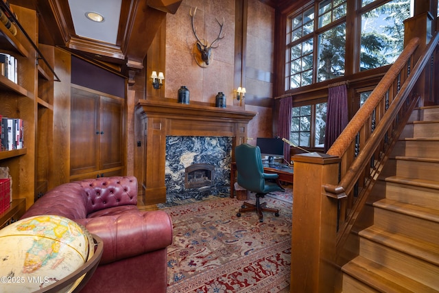 office featuring wooden walls, a towering ceiling, a fireplace, and ornamental molding