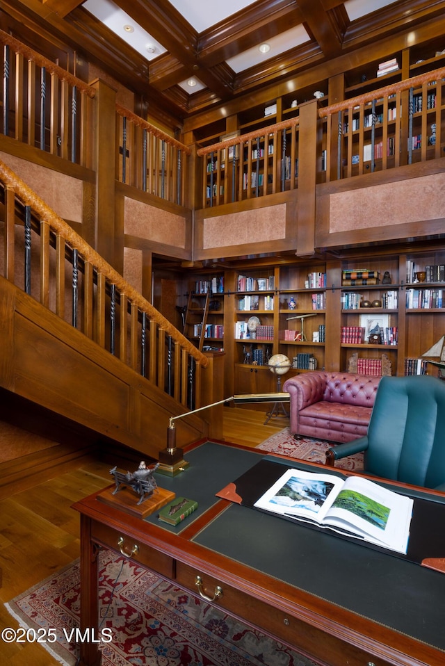 interior space featuring beamed ceiling, coffered ceiling, a towering ceiling, and wood finished floors