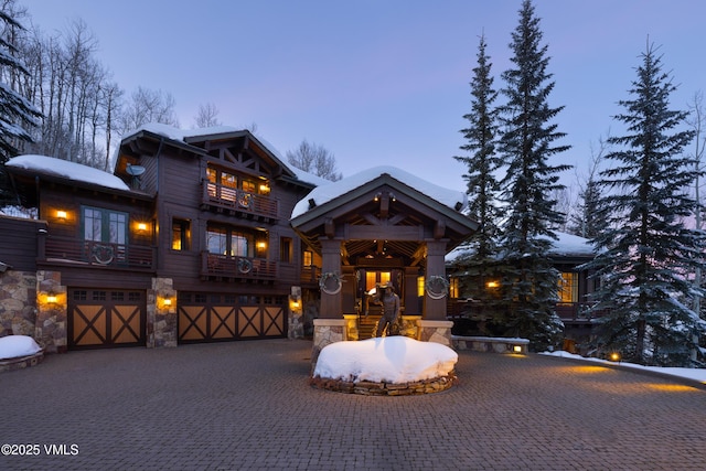 view of front of house featuring a garage, a balcony, decorative driveway, and stone siding