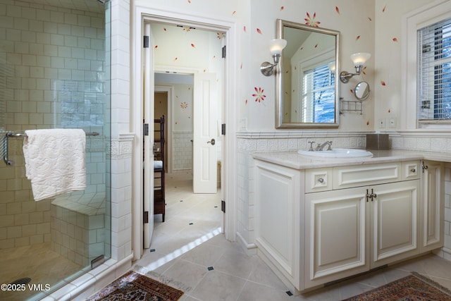 bathroom with tile patterned floors, wainscoting, tile walls, and a shower stall