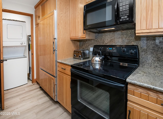 120 Offerson Rd Unit D330, Beaver Creek, CO 81620 - kitchen featuring black appliances, stacked washer and clothes dryer, decorative backsplash, light wood finished floors, and light stone counters