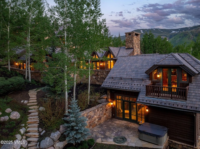 1094 Riva Gln, Vail, CO 81657 - back of house at dusk featuring a balcony, a patio area, and a chimney