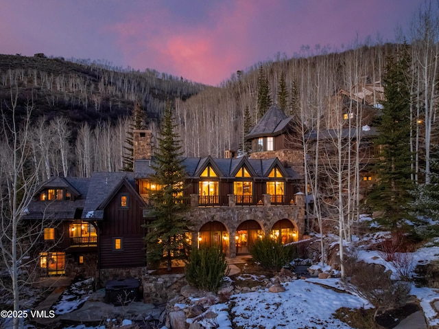 1094 Riva Gln, Vail, CO 81657 - snow covered property featuring a balcony, stone siding, board and batten siding, and a wooded view