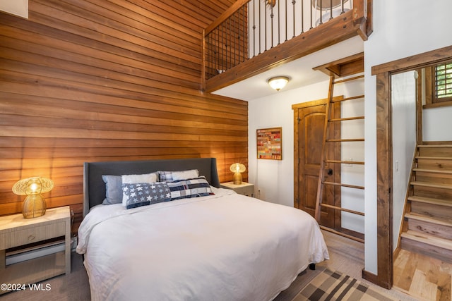 bedroom featuring a towering ceiling and wood walls