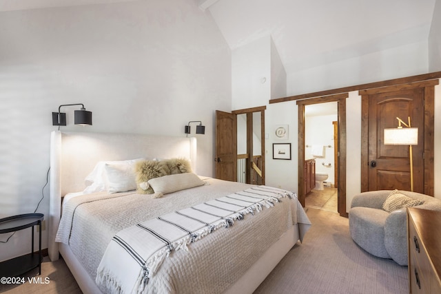 bedroom featuring lofted ceiling, connected bathroom, and light carpet