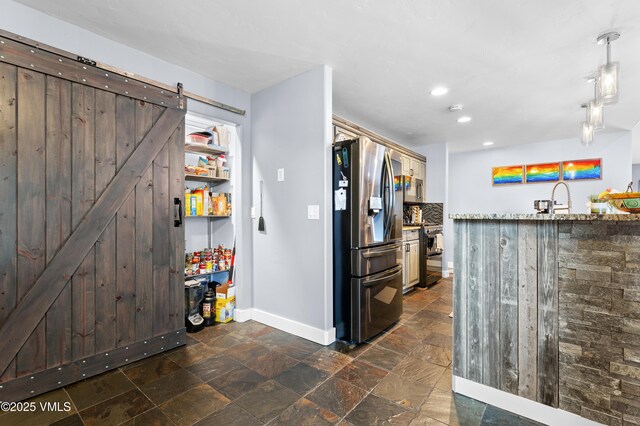 kitchen with pendant lighting, sink, stainless steel appliances, and a barn door