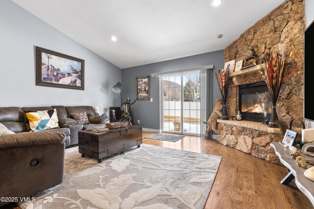 living room featuring lofted ceiling, a fireplace, and light hardwood / wood-style floors