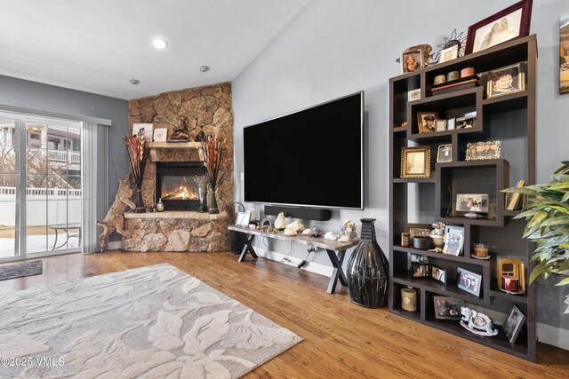 living room featuring a stone fireplace and hardwood / wood-style floors