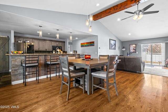 dining space with a barn door, dark wood-type flooring, vaulted ceiling with beams, and ceiling fan