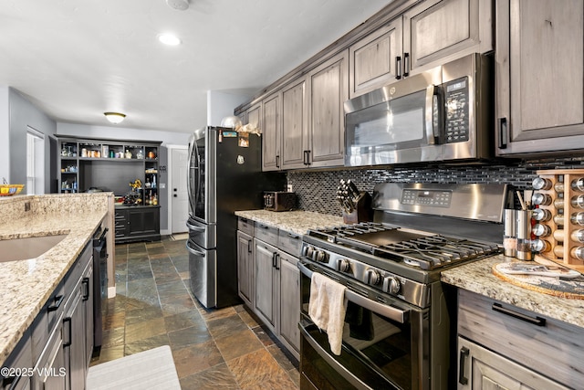 kitchen with sink, appliances with stainless steel finishes, backsplash, dark brown cabinets, and light stone counters