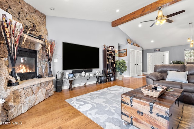 living room featuring a fireplace, light hardwood / wood-style flooring, lofted ceiling with beams, and ceiling fan