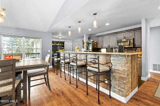 kitchen featuring hanging light fixtures, backsplash, a breakfast bar area, and dark hardwood / wood-style floors