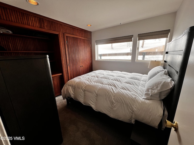 bedroom with wooden walls and dark carpet