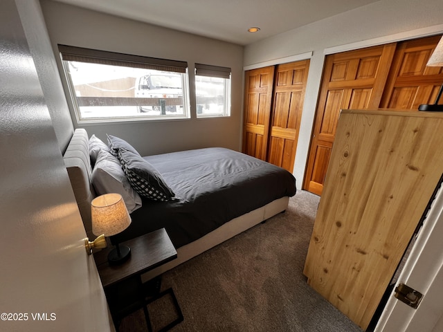 bedroom with multiple closets and dark colored carpet