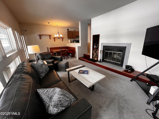 living room with carpet floors, a glass covered fireplace, and an inviting chandelier