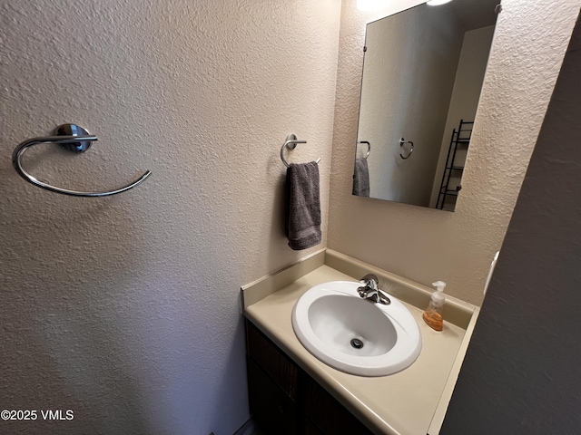 bathroom featuring a textured wall and vanity