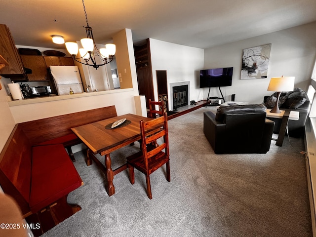 carpeted dining area featuring a notable chandelier and a glass covered fireplace