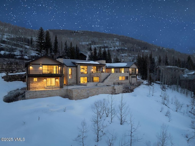 1326 Spraddle Creek Rd, Vail, CO 81657 - snow covered rear of property with stone siding and a wooded view