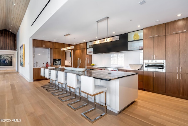 1326 Spraddle Creek Rd, Vail, CO 81657 - kitchen with modern cabinets, light wood-style flooring, a kitchen breakfast bar, open shelves, and brown cabinetry
