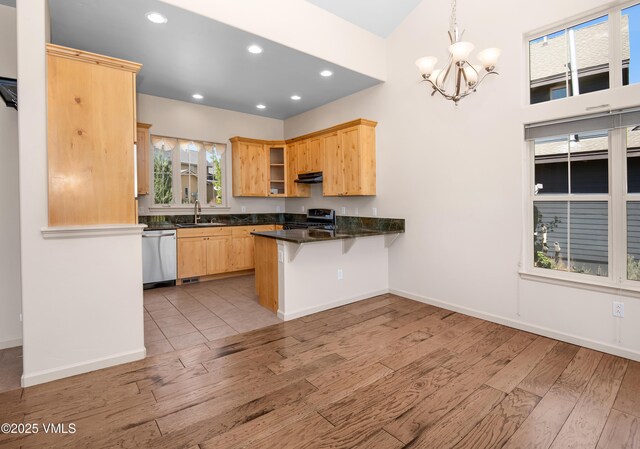 kitchen with appliances with stainless steel finishes, a peninsula, dark countertops, light wood-style floors, and recessed lighting