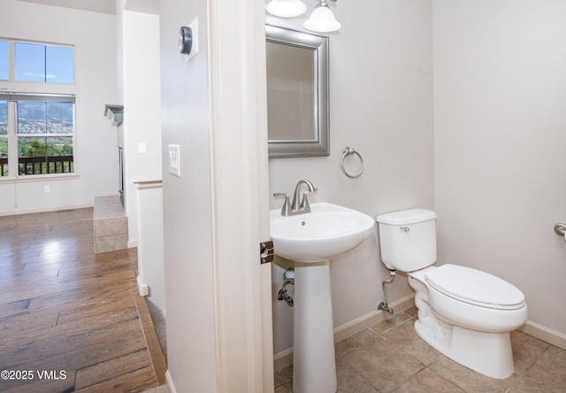 bathroom with baseboards, toilet, and a sink