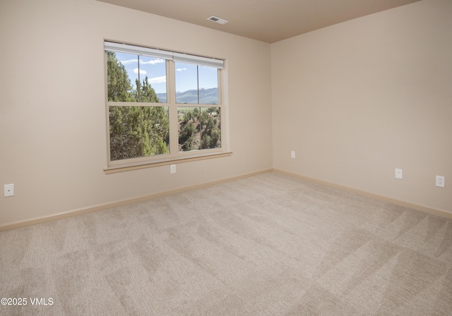 spare room with carpet, baseboards, and a mountain view