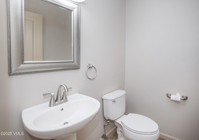 bathroom featuring a sink, baseboards, and toilet