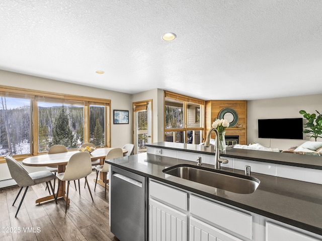 kitchen with dishwasher, sink, a brick fireplace, and white cabinets