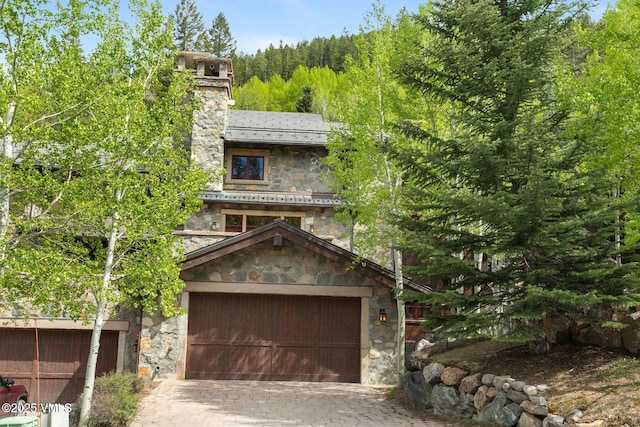 102 Village Walk, Beaver Creek, CO 81620 - view of front of property with a wooded view, a garage, stone siding, and decorative driveway