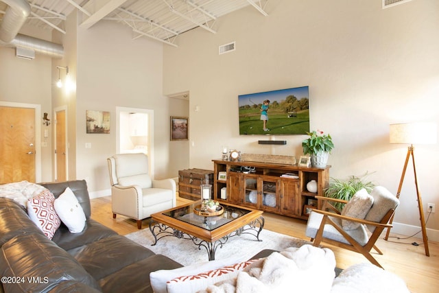 living room with a towering ceiling and light hardwood / wood-style flooring