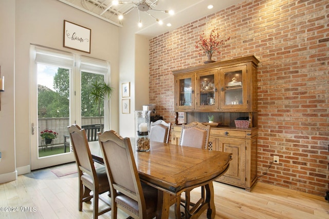 dining space with brick wall and light hardwood / wood-style floors