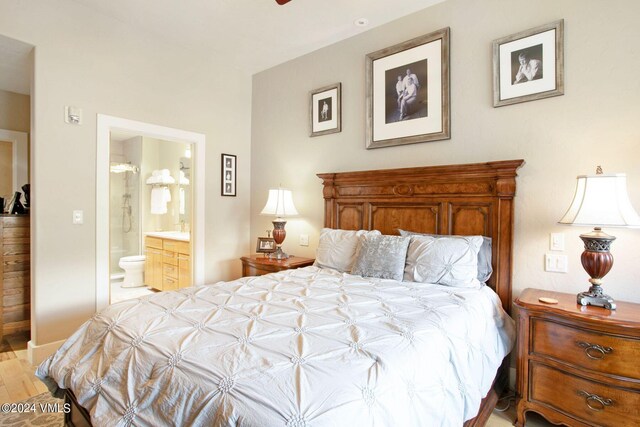 bedroom featuring ensuite bath, light hardwood / wood-style floors, and sink